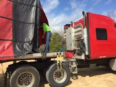 Mechigian removes cords from the tarp so it can be removed. (Photo: Deanne Winslett)