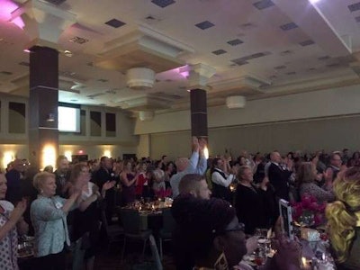 Highway Diamond Gala attendees cheer after driver and veteran Tiffany Hanna's national anthem performance.