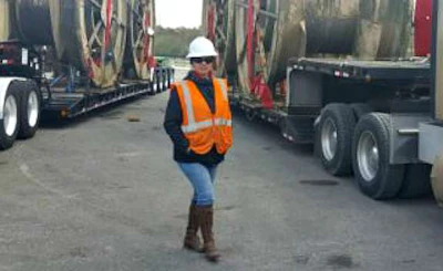 Cynthia De La Rosa stands between two ACME trucks with oversize loads. The truck on the right of the picture is hers. (Image Courtesy of Cynthia De La Rosa)