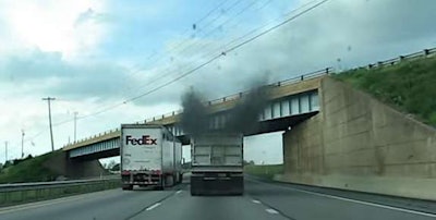 Semi truck with smog from stacks next to a FedEx truck