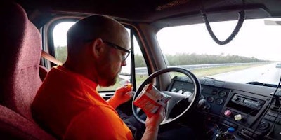 Driver in Starsky Robotics autonomous truck enjoying a snak