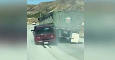 Screen shot from a video that shows a car being dragged behind a truck in California.