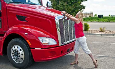 Woman trucker opening the hood of truck
