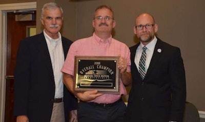 AAA Cooper Transportation driver Mark Knight, center, was named grand champion at the Alabama TDC. He was presented the award by Alabama Trucking Association Chairman of the Board Terry Kilpatrick of Billy Barnes Enterprises, left, and Alabama Trucking Association Council Chairman Tony Smith of AAA Cooper Transportation, right. (Image Courtesy of Alabama Trucking Association/Facebook)