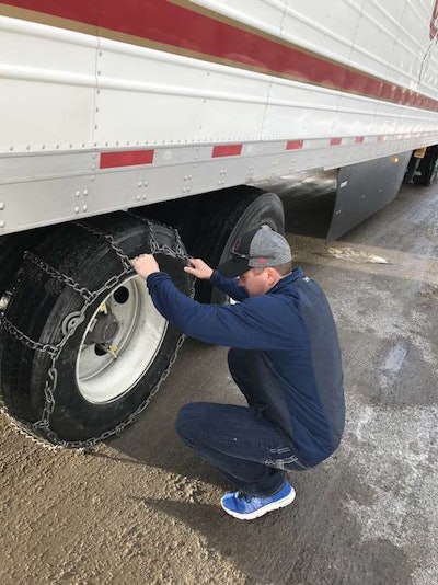 KC McCann, C.R. England's vice president of operations, examines chains on a tire during a March trip over Donner's Pass in California. (Image Courtesy of C.R. England)