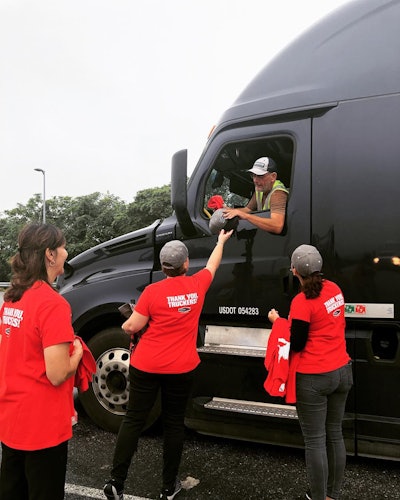 Criss Kerkendall, Mary Wauls, and Gina Bonafede give a hat and other RoadPro merchandise to a driver at the Lawn Travel Plaza.