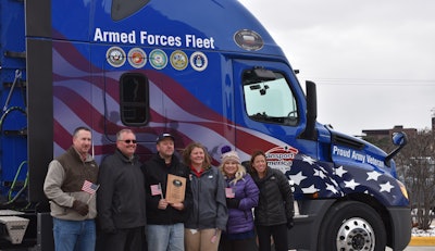 From left to right: Phill Reynolds, vice president of maintenance; Marv Stolz, fleet leader; Russ Cox, driver; Steph LaVictoire, team leader; Katie Talcott, vice president of driver relations; and Laura Rahier, director of driver relations, stand in front of the first Armed Forces Fleet truck. (Image Courtesy of Transport America)