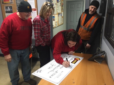 Estes employees add their names to a check aiding one of several charities (Estes photo)