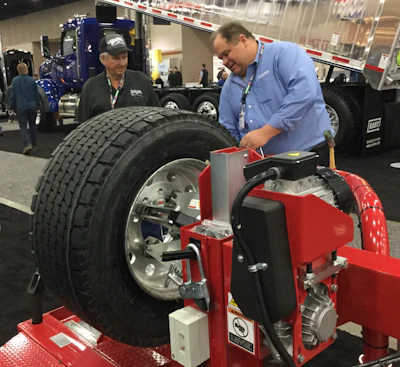 John Trollinger, an owner-operator from Oklahoma watches Chris Grote work one of Hunter Engineering's tire machines.