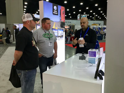 Aaron Van Loon (left) and Jeremy Helton (middle) learn about the driver devices from Venky Rao at the Rand McNally booth.