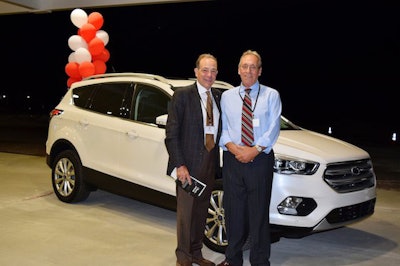 Pat Gallagher, PGT’s founder, stands with driver Glenn Gray in front of a Ford Escape Titanium. Gray won the vehicle in a raffle at the awards event. (Image Courtesy of PGT Trucking)