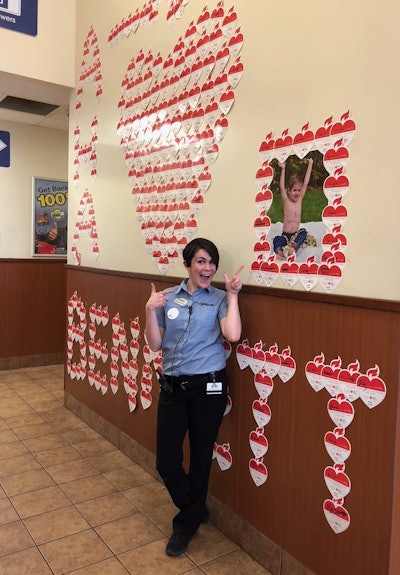 Hannah Lewis stands near a wall of American Heart Association hearts and a photo of her son at the Pilot Travel Center in Lebanon, Tennessee during the Life is Why We Give campaign in February 2019.