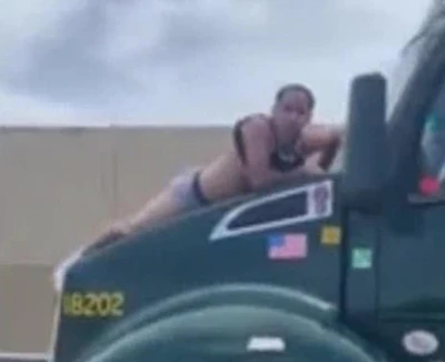 A man clings to the hood of a moving tractor-trailer in Florida