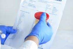 gloved hands holding a urine sample and drug test results
