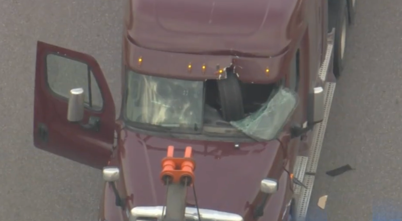 Semi truck with tire smashed through its windshield