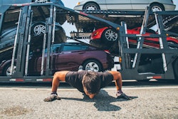 Truck driver doing pushups next to his car carrier
