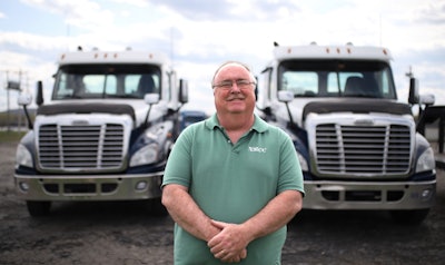 College CDL instructor Dennis Dyer in front of two trucks