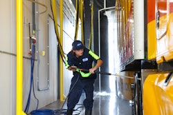 Attendant washing a tractor-trailer
