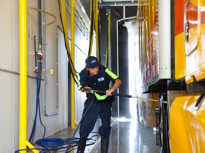 Attendant washing a tractor-trailer