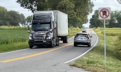 Tractor-trailer on rural road with 'No Truck' sign