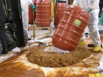 Customs and Border Patrol officers remove drugs from barrels of jalapeno paste
