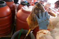 CBP officer take drugs from barrel of jalapeno paste