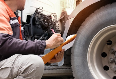 Man holding clipboard inspects truck