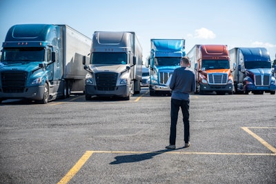 Truck driver in parking lot with several big rigs