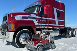 Red Mack truck pictured with child and dog in toy Mack