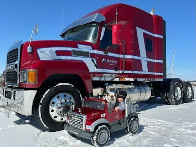 Red Mack truck pictured with child and dog in toy Mack