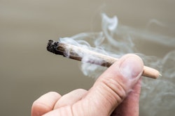 Someone holding a burning marijuana cigarette