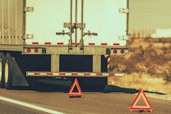 Tractor-trailer on the side of the highway with two warning triangles