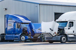 Two trucks with hoods up waiting for repairs