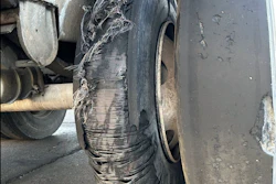 Damaged truck tire with severe tread separation and debris wrapped around the wheel