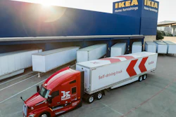 Red Kodiak autonomous delivery truck with white trailer parked at IKEA loading dock with white shipping containers