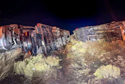 Two overturned vehicles at night on desert terrain with sparse vegetation