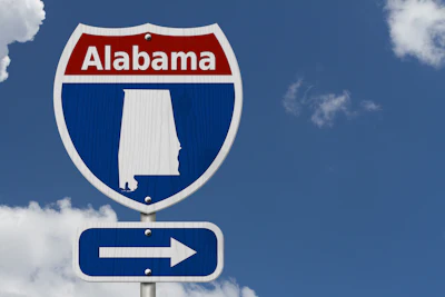 Alabama interstate highway sign with directional arrow pointing right against blue sky