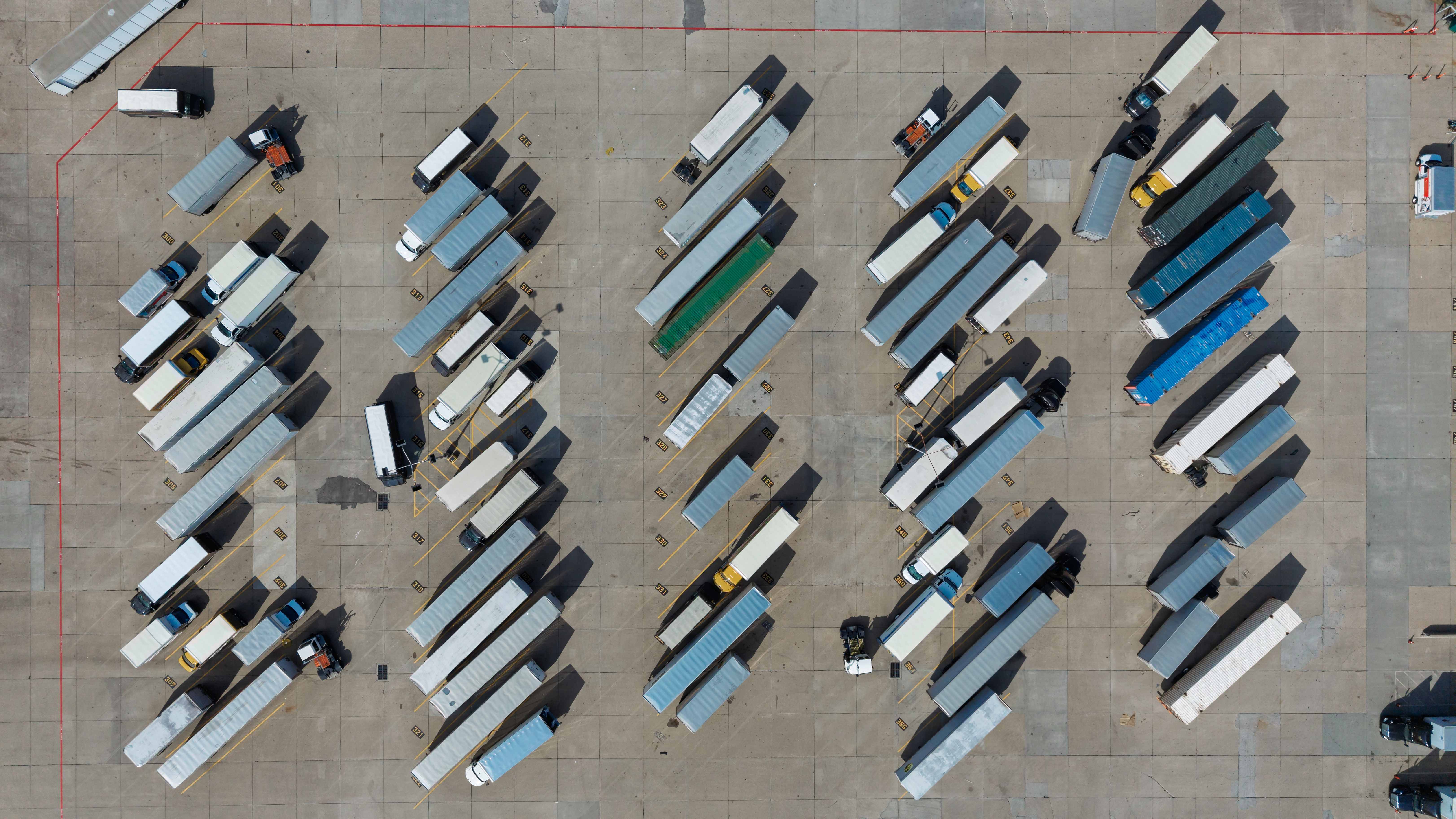 Aerial view of organized truck parking lot with multiple commercial vehicles in rows