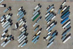 Aerial view of organized truck parking lot with multiple commercial vehicles in rows