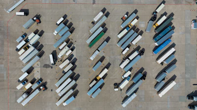 Aerial view of organized truck parking lot with multiple commercial vehicles in rows