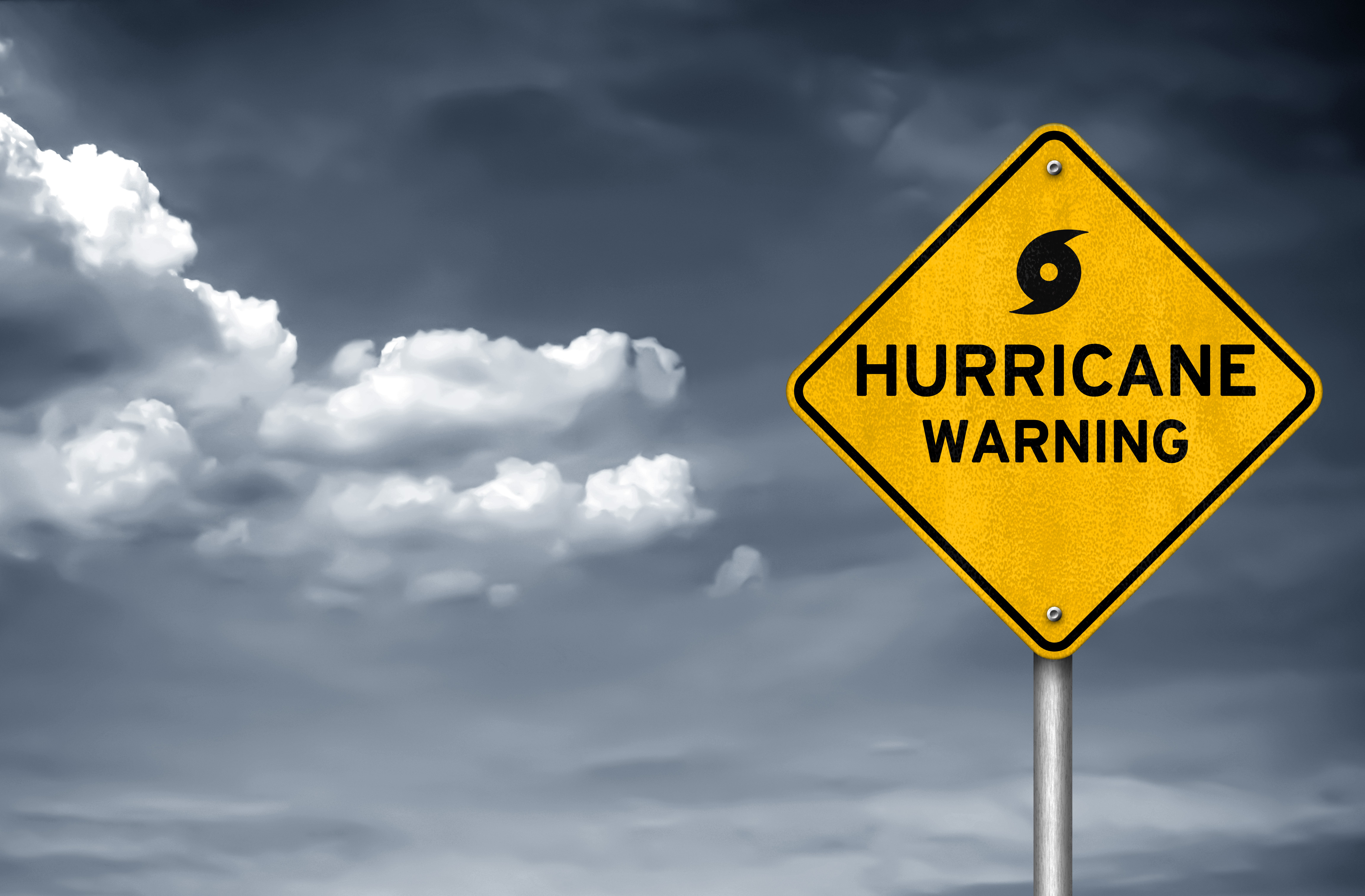 Yellow diamond hurricane warning sign against stormy sky with dark clouds