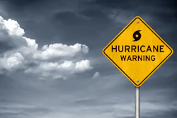 Yellow diamond hurricane warning sign against stormy sky with dark clouds