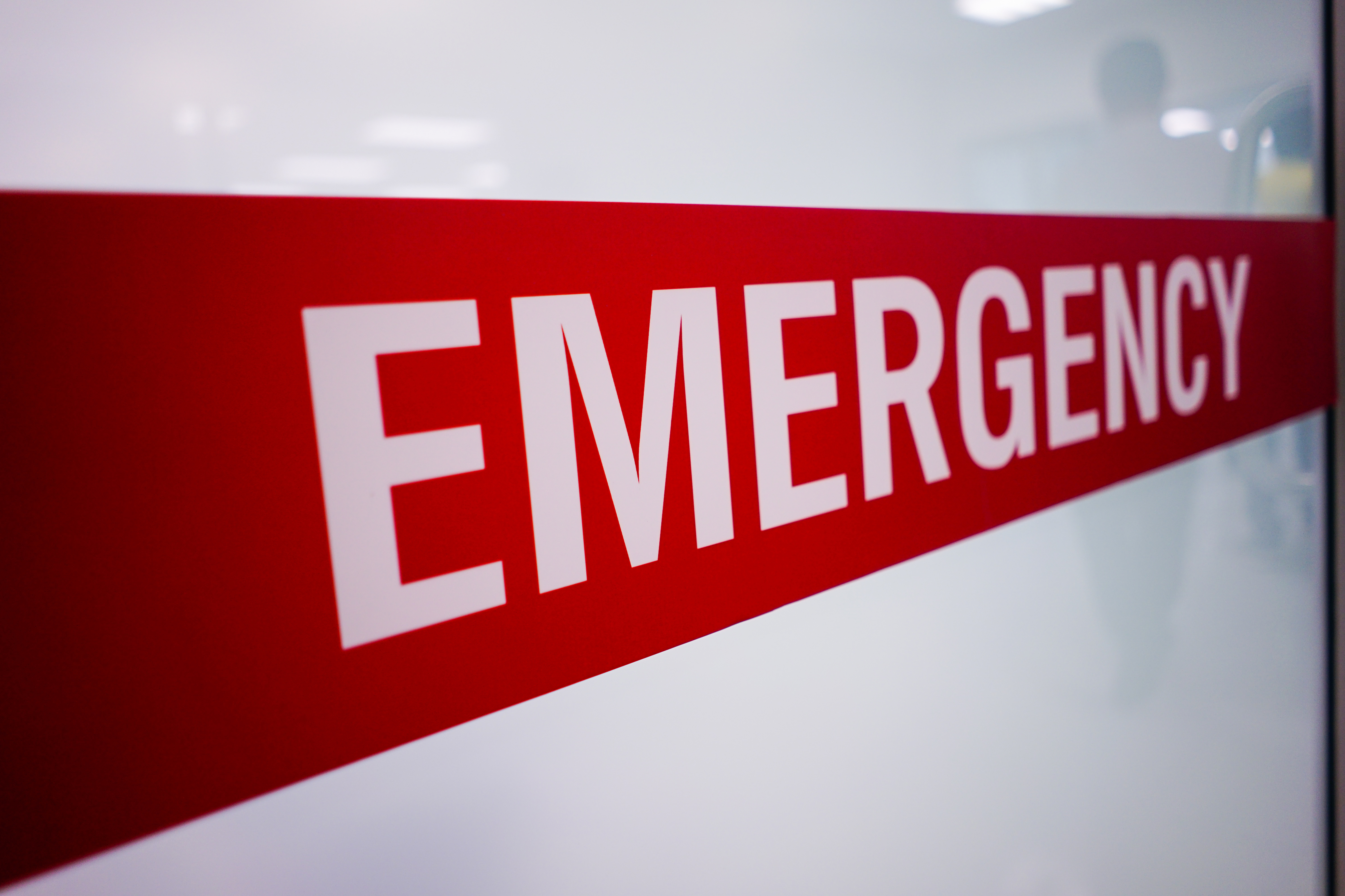 Red and white emergency sign with bold white lettering on diagonal stripe