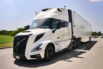 White Volvo semi-truck with refrigerated trailer driving on highway with green landscape