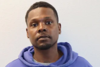 Portrait of a man wearing a blue hoodie against a white background