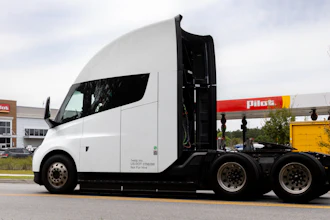 White and black semi-truck with open door at commercial facility with Pilcs signage