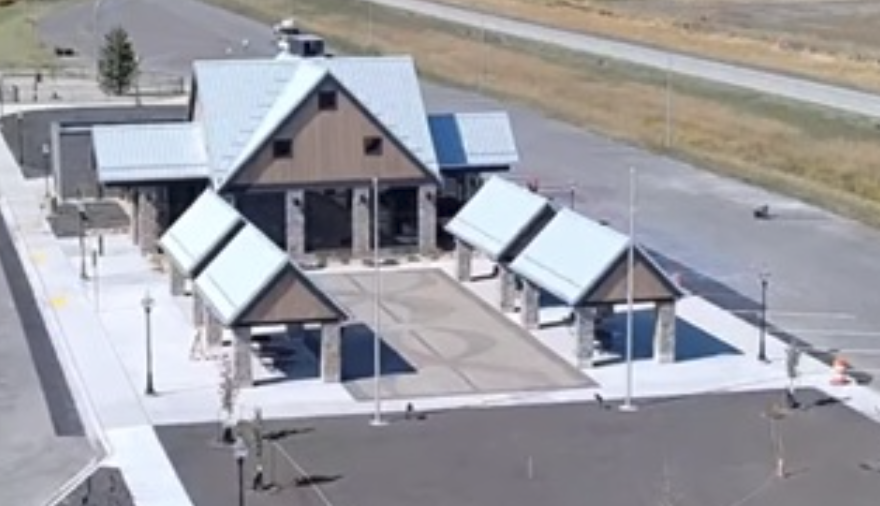 Aerial view of modern building with peaked roofs and solar panels in rural landscape