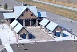 Aerial view of modern building with peaked roofs and solar panels in rural landscape