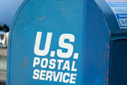 Blue U.S. Postal Service mailbox with collection schedule sign and white text branding