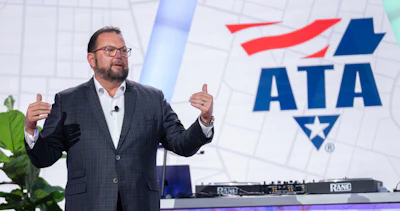Professional speaker presenting at ATA conference with audio equipment and branded backdrop